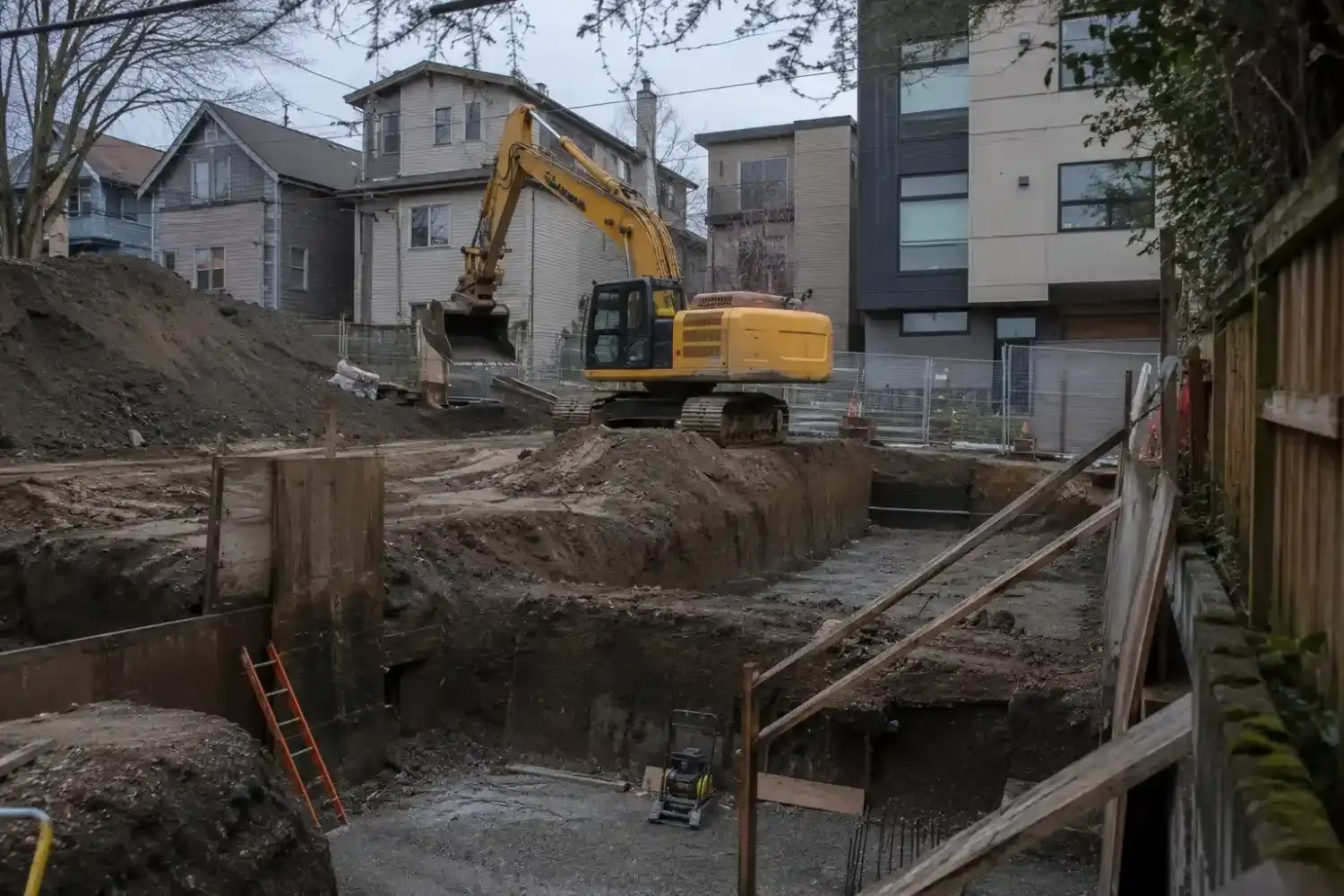An excavator cutting and grading a residential building pad on a cleared Puget Sound lot