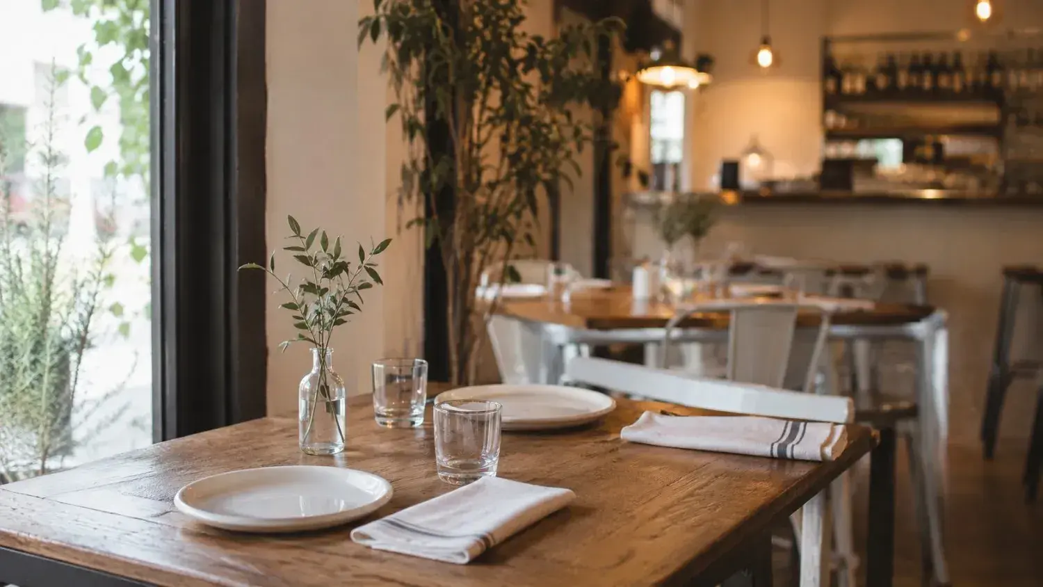 An inviting restaurant table setting with white plates and glassware beside a window